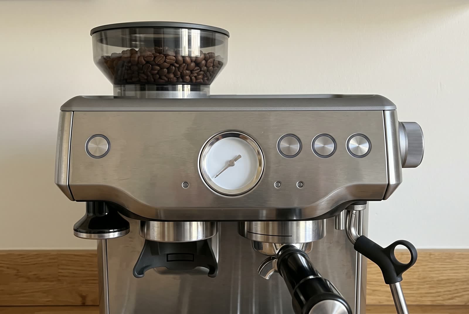 A close crop of an espresso machine's front panel: a blank gauge, plain buttons, a steam knob.